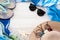 Summer beach accessories. Colorful flip flops, shell, black sunglasses, blue pareo and straw hat on a wood background. The concept