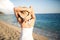 Summer beach fashion woman enjoying summer and sun,walking the beach near clear blue sea,putting her hands behind her