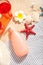 Summer beach, travel, holiday, vacation concept. Tube of sunscreen, starfish, plumeria frangipani, cold drink and