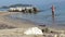 Summer. Beautiful sea beach. A girl in a red swimsuit knee-deep in water. She plays with water, hands splashes water up