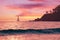 Summer beautiful seascape - pink sky at sunset, warm sea, sailboat on horizon, palm tree silhouette.