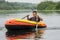 In summer, the boy floats on the river in an inflatable boat. He shows his hand super