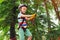 Summer camp. Boy passing the cable route high among trees. Climbing the rope park