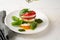 Summer caprese salad on white plate with basil pesto