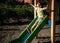 Summer, childhood, leisure, friendship and people concept - happy little boy on children playground slid from the hill