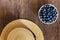 Summer close-up of blueberries and straw hat on vintage wooden background.