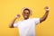 Summer clubbing. Young black guy dancing to favorite music with his hands up on yellow background