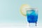 Summer cold blue lagoon drink with lemon slice, ice cubes, salt rim in elegant shot glass on pastel mint background.