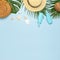 Summer composition flat lay. Round trendy rattan bag straw hat tropical palm leaves coconut sunscreen seashells on blue background