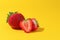 Summer composition fruits, berries. Two of freshly ripened strawberries on a yellow background