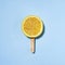 Summer concept lemon on a stick instead of ice cream - A piece of juicy lemon on a blue background