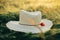 Summer countryside. Rustic straw hat and red poppy on barley ears in in sunset light in field. Wildflowers and farm hat close up