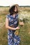 Summer in countryside. Stylish young woman in blue vintage dress and hat walking with white wildflowers in summer meadow. Happy