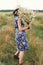 Summer in countryside. Stylish young woman in blue vintage dress and hat walking with white wildflowers in summer meadow. Happy