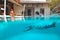 Summer. Couple Having Fun At Pool On Vacation. Man Diving Underwater And Splashing Turquoise Water.