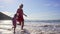 Summer day on beach near ocean. Woman with little girl walks on beach coast.