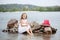 Summer day. Happy childhood carefree game on the open sand. The concept of rest. Little cute girl and scarlet sails. Girl sitting