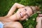 Summer daydreams. Pretty young blonde woman lying on the grass while looking up and smiling.