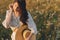 Summer delight and travel. Stylish boho woman with straw hat posing among wildflowers in warm sunset light. Young female in rustic