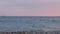 Summer evening at sea coast. Small waves surf on gray pebbles.