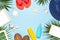 Summer fashion flat lay. Blue hat coral flip flops tropical palm leaves sunscreen white photo frame coconut seashells starfish on