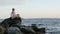 Summer fashion hipster woman in beautiful dress sitting on the stone at beach