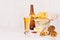 Summer fast food - different crunchy snacks, red and curry sauce, lager beer in glass and brown bottle on soft white wood board.