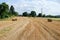 Summer field of hay and harvest with haystacks in a small village. Harvesting, haymaking and agriculture photography.