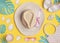 Summer flat lay. Beach accessories with shells and tropical leaves on yellow background, top view. Straw hat, sunglasses, sandals