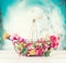Summer flowers in basket on table at turquoise blue sky background, fron view