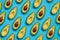 Summer food pattern. Avocado halves on blue background. Top view. Flat lay