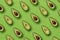 Summer food pattern. Avocado halves on green background. Top view. Flat lay