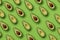 Summer food pattern. Avocado halves on green background. Top view. Flat lay