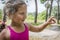 In the summer in the forest, a little curly girl holds a lizard in her arms