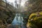 A summer forest. A man going straight in the forest avoiding the river stepping on the rocks