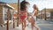 Summer fun, happy slender young girls in swimsuits have fun running along seafront with bungalows against backdrop of