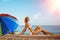 Summer fun holiday woman on summer landscape with rainbow umbrella. Girl with tanned body lying on the beach under the sun and bl