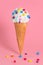 Summer funny creative concept of wafer cone with melting ice cream covered and strewed colorful chocolate confetti on pink