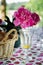 summer garden party table with bread in wicker basket, tasty lemonade and pink peonies