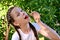 in the summer garden young cute girl with pigtails in white T-shirt brings one ripe cherry berry to her mouth.