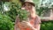 Summer gardening. Portrait of young woman holds flowering potted plant in hands.