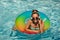 Summer girl in swimming pool. Cute funny teen relaxing with toy ring floating in a swimming pool having fun during
