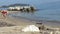 Summer. Greece. Beautiful day on the beach. A young woman  in a swimsuit throws stones into the sea.  It`s a lonely charming plac