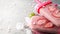 Summer heat: refreshing pink fruit ice with strawberry pieces surrounded by transparent and green ice cubes on a gray table.