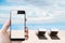 Summer holiday, hand holding mobile smartphone on the beach in summer