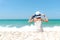 Summer Holiday. Lifestyle woman white dress wearing fashion summer trips sitting on the sandy ocean beach. Happy woman enjoy and r