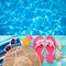 Summer Holidays in Beach Seashore. Fashion accessories summer flip flops, hat, sunglasses on bright turquoise board near the pool