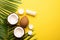 Summer holidays concept. Top view photo of white sunscreen bottle cream jars cracked coconuts and palm leaves on isolated yellow b