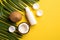 Summer holidays concept. Top view photo of white sunscreen bottle cream jars cracked coconuts and palm leaves on isolated yellow b