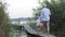 Summer holidays, little boy with fishing rod goes to pier among reeds with father and snack basket to fish on family